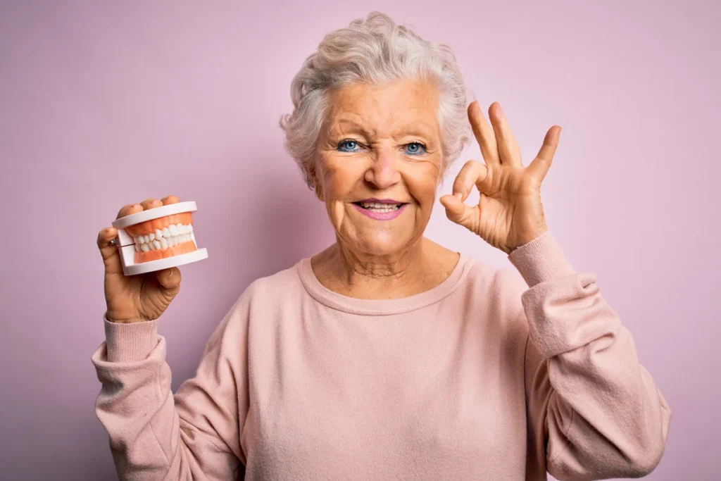 Old woman holding her dentures