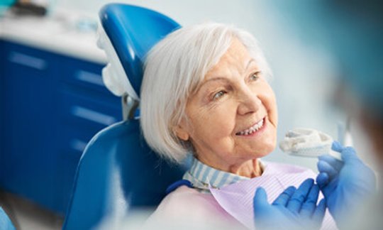 Dentist showing a partial denture to a smiling patient